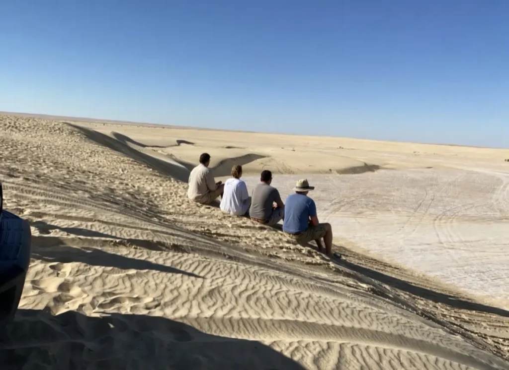 what to do in Tunisia Sahara desert dunes travelers sitting panoramic landscape